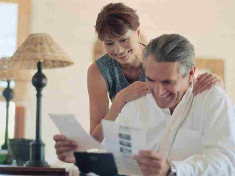 Due pensionati sorridono guardando dei documenti